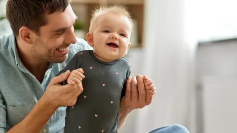 father holding baby and smiling 
