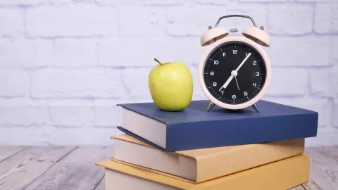 Apple and clock on a stack of books