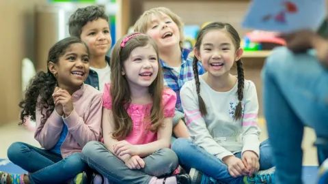 group of children sitting on floor listening to book being read